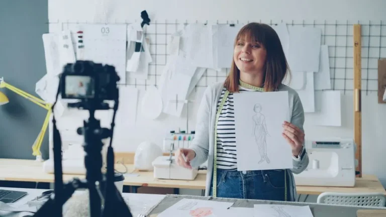 Smiling fashion designer presenting sketch in studio, being recorded on camera.