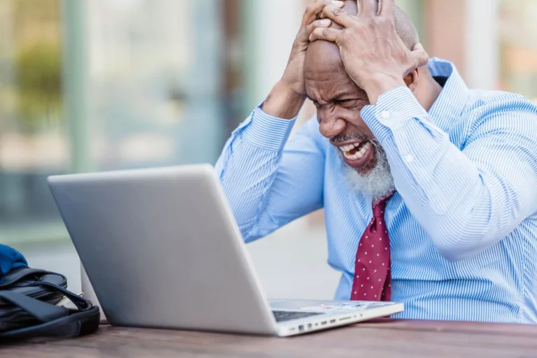 Homem afro-americano demonstrando frustração com laptop em ambiente externo, representando erros comuns landing page