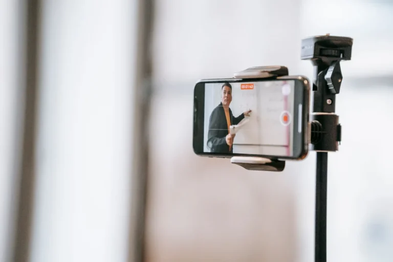 Apresentador gravando aula online com celular em tripé, guia de monetização de cursos online
