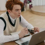 Jovem concentrado em aprendizado online em casa, usando laptop e caderno, representando melhores práticas EAD