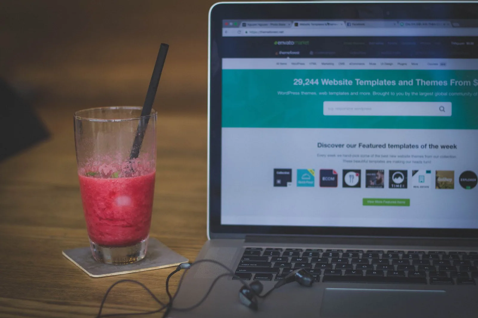 Vitamina de fruta ao lado de um notebook que exibe um site, unindo trabalho e pausa